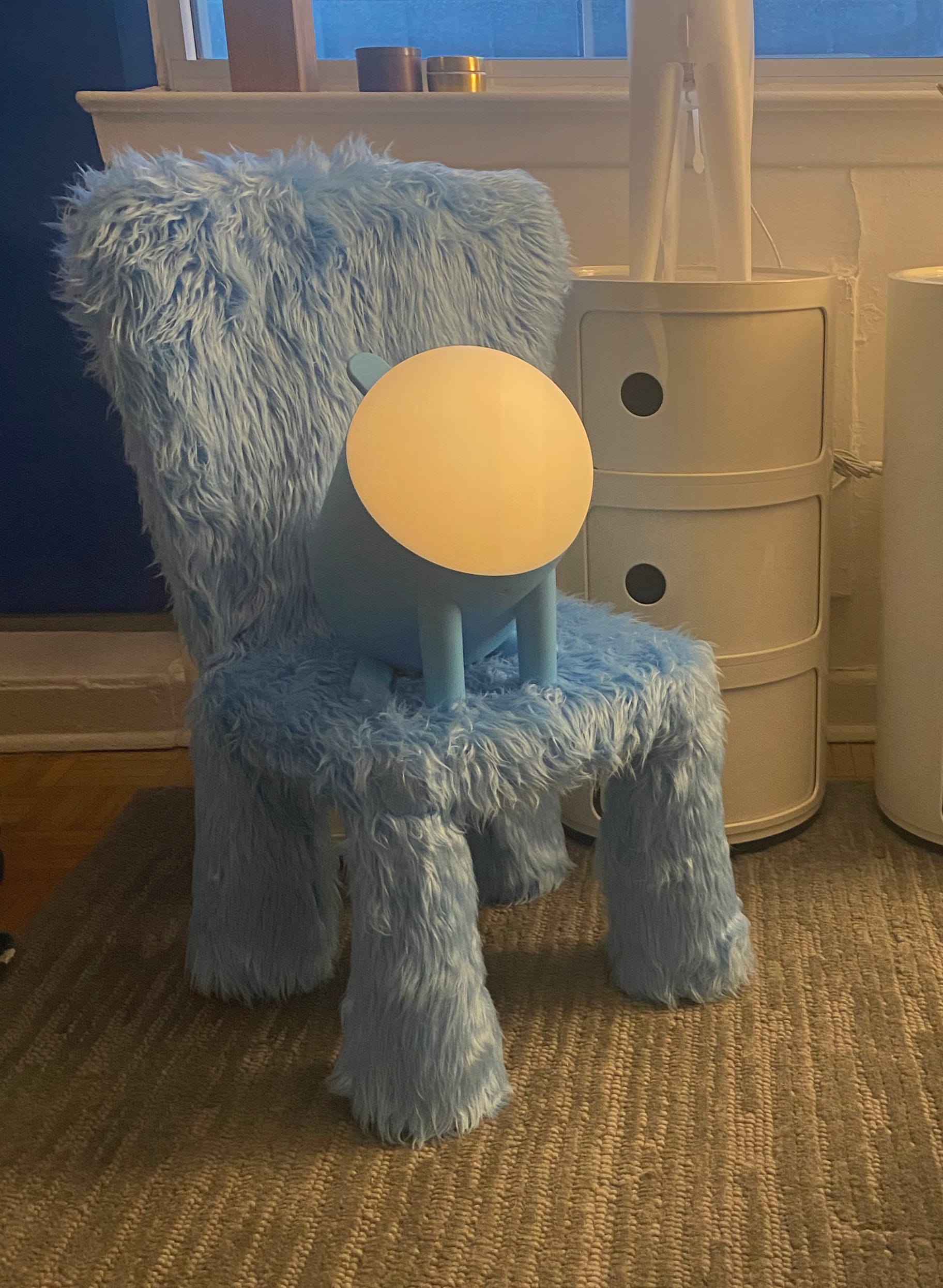 Furry blue chair in my living room with dog lamp on the seat.
