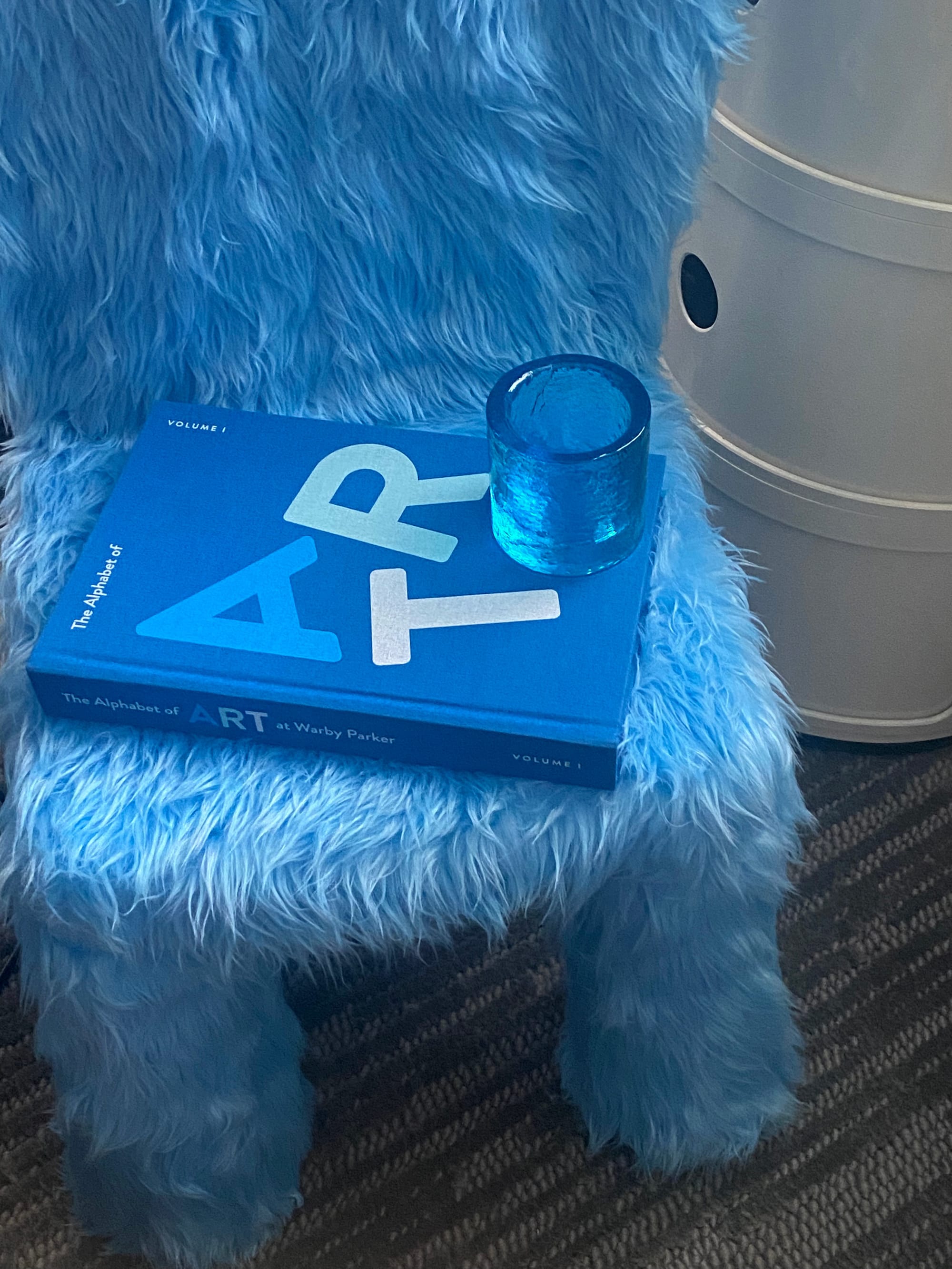Blue book and blue candle holder on furry blue chair.