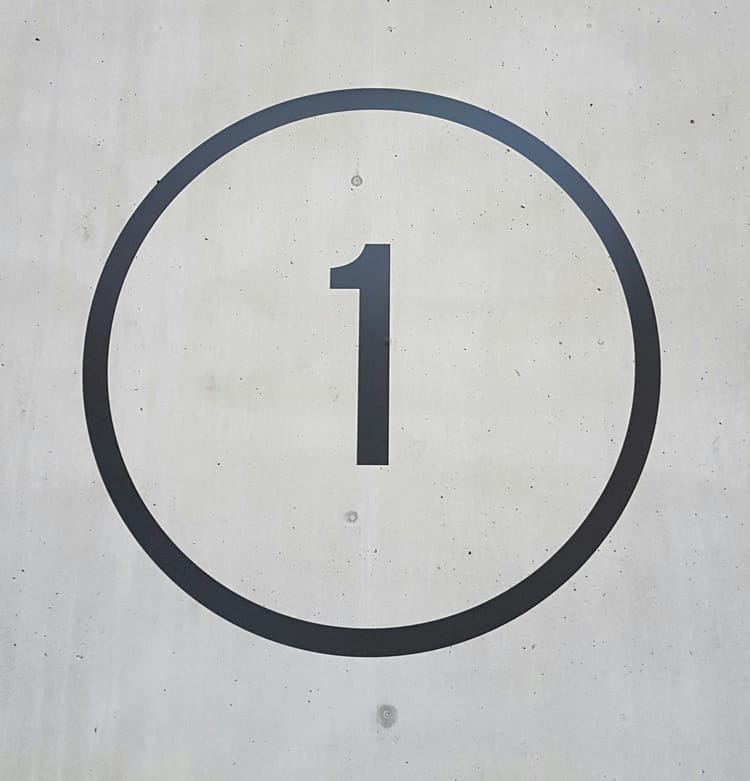 A number one inside a circle with a concrete background.