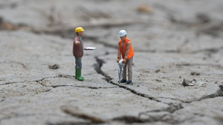 Two construction worker figurines, one with a jackhammer, the other with a clipboard.