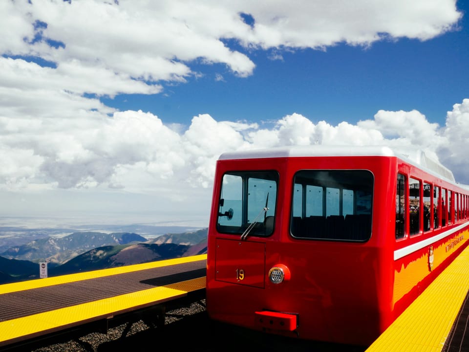 Red tram with yellow platforms on either side and a blue sky in the background.