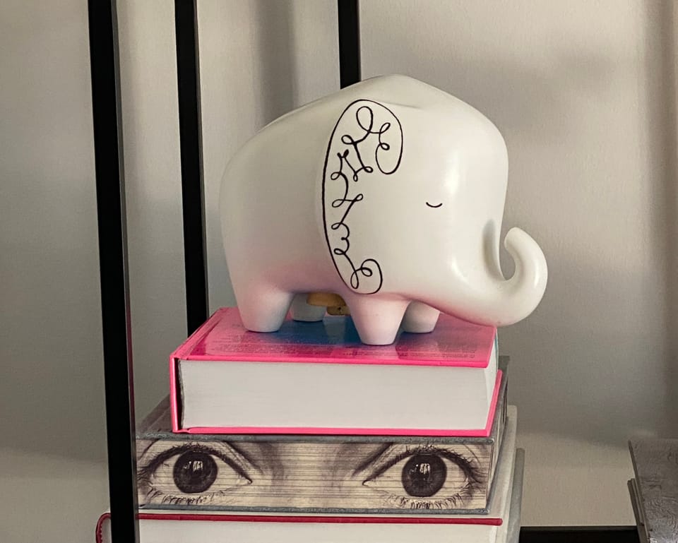 Elephant piggy bank on a stack of books.